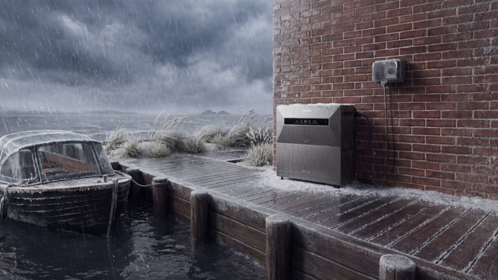 Are you hesitant about placing a home battery outside? Anker Solix portable power station (black) against a brick wall in stormy, wet weather by the water’s edge, with a snow-covered old wooden boat and gray, cloudy skies