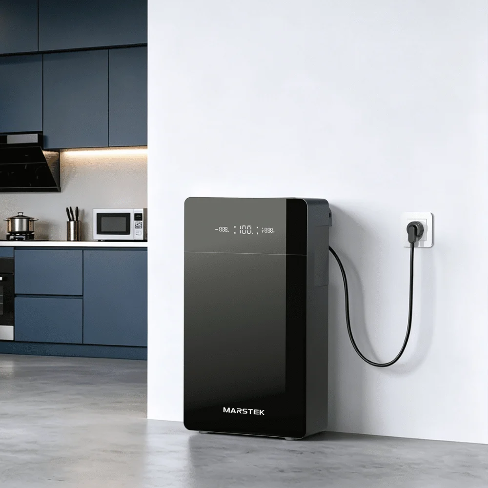 Marstek black home battery model with digital display, mounted on a white wall and blue kitchen cabinet in the background
